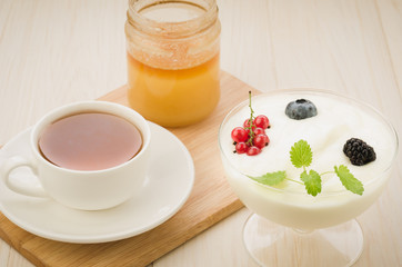 breakfast from yogurt with berries, tea and honey/breakfast from yogurt with berries, tea and honey on a wooden tray.
