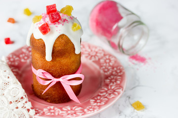 Easter cake kulich decorated white frosting, pink sugar and candied fruit