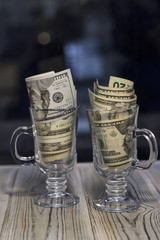 Fototapeta na wymiar United States money in two glasses on the table. Rough boards background. Money concept. Closeup