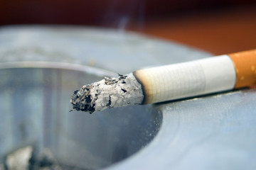 Part smoked cigarette burning on an ashtray