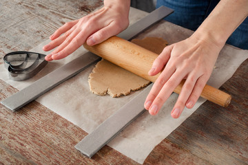 woman with her hands rolls pastry for a cookie with a rolling pin