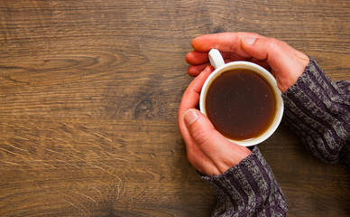 Cup of black tea in the hands of man. on a wooden background. with copy space. top view
