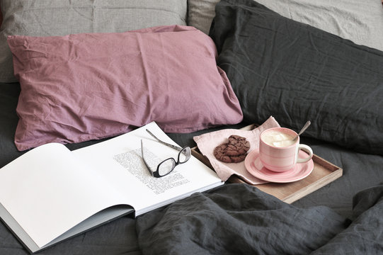 Breakfast in tray and open book with glasses in bed