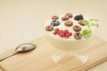 chocolate flakes with yogurt and berries in glass bowl/chocolate flakes with yogurt and berries in glass bowl on a wooden tray.Copy space. Toned