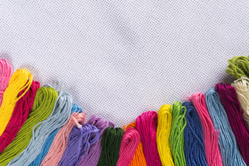 Colored thread for embroidery on white canvas. Copy spase.