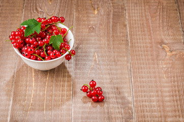 red currant in a white bowl on a wooden background/red currant in a white bowl on a wooden background. Top view. copy space