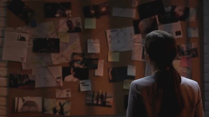 Lady private agent looking at crime investigation board, drinking cup of coffee