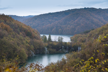 A fall afternoon with changing colors and multiple waterfalls in the distance. The weather is overcast.