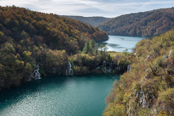 Two lakes showing the different levels and heights of Plitvice Lakes National Park. This was taken in the fall in Croatia. There are two waterfalls rushing water from the higher elevation to the lower