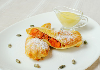 a pumpkin pie with sugar powder and sweet sauce in a white plate, a cozy light table setting, a restaurant feed