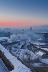 The railway in the city. Industrial quarter in a big city. Sunrise. Vertical shot.