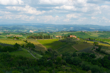Fototapeta na wymiar Rolling hills of Tuscany in summer with glowing sunshine and a villa in view