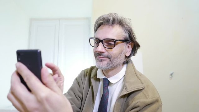 Mature man looking at smartphone in his office