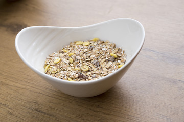 white bowl full of healthy oatmeal with fruits on wooden table