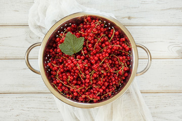 Colander full of freshly harvested red currants on board. Top view.