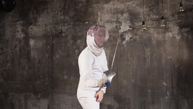 persons in a protective helmet on the head actively train sports fencing in a special form, he deftly twists with a sharp weapon called a rapier, an athlete prepares for competitions