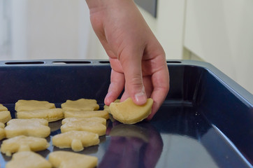 The boy lays out the pastry cookies on the baking sheet