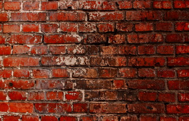 A weathere rough dirty red brick wall with traces of cracked white paint and black spots background as a basis for the thematic design and unusual creative concepts