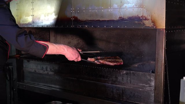 the chef turns over the grilled steak in a steakhouse