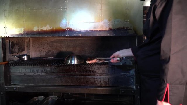 the chef turns over the grilled steak in a steakhouse