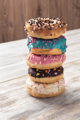 glazed donuts with sprinkles folded in pile on white wooden table