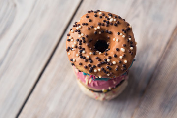 glazed donuts with sprinkles folded in pile on white wooden table