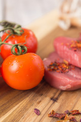 beef steak with vegetables and spices on a cutting Board, a white wooden table
