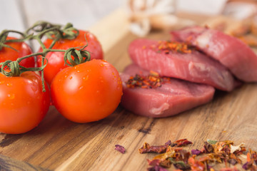 beef steak with vegetables and spices on a cutting Board, a white wooden table