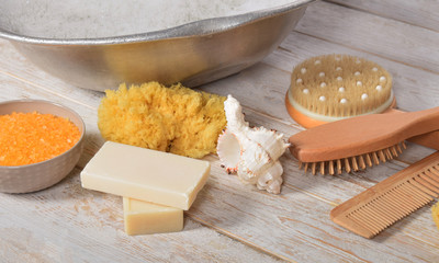 natural gray soap next to a grandmother's metal bowl with salt for a bath with a natural sponge brush and a comb with a free space for text
