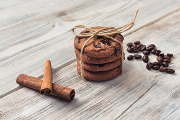 chocolate chip cookies tied with twine with coffee beans and cinnamon stick on white wooden table