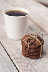 chocolate chip cookies tied with twine and white coffee Cup on white wooden table