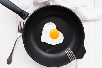 heart-shaped fried eggs in a black pan