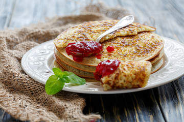 Stack of pancakes and teaspoon with berry jam.