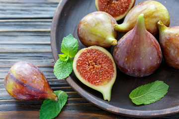 Fresh figs and mint leaves on a wooden platter.