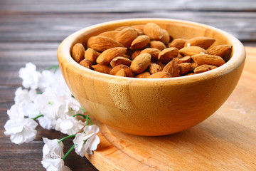 Raw dry nuts of almonds in a wooden bowl on a wooden table.