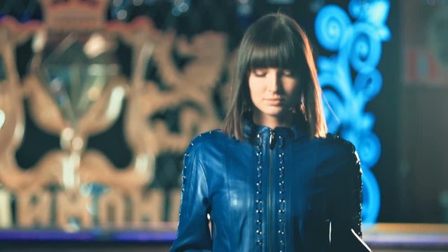Young fashion woman in leather jacket walking in night club