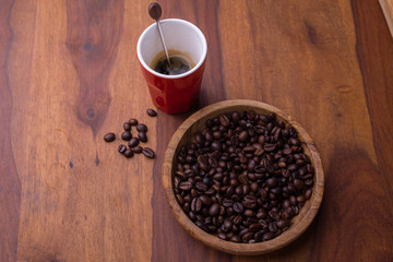 A cup of coffee and coffee beans in a wooden plate