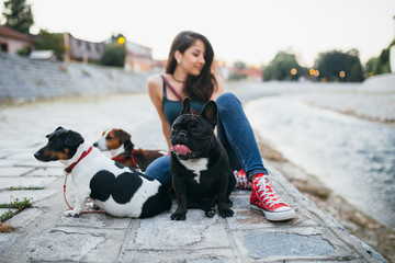 Dog walker with dogs enjoying outdoors next to city river. 