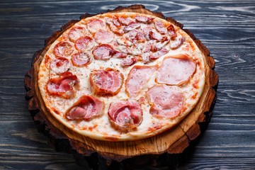 Appetizing fresh baked pizza with salami, bacon, ham and pepperoni served on wood. Restaurant menu photo, Italian food concept