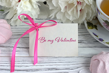 Valentines day greeting card with white peonies tea cup marshmellow and lettering.