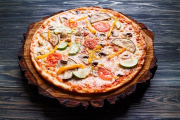 Appetizing vegetarian pizza with tomato, zucchini, eggplant, olives and mushrooms close up. Delicious Italian food, restaurant menu photo