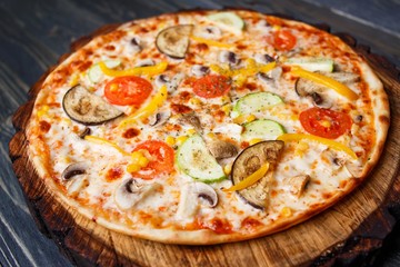 Delicious fresh vegetarian pizza with tomato, zucchini, eggplant, olives and mushrooms served on wood. Italian food for vegetarians