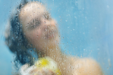 Defocused female model washes hair and applies shower gel on skin, bathes in shower cabine, feels relaxed and clean, forgets about her daily routine. People, lifestyle and refreshment concept