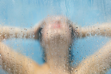 Unrecoginzable female woman relaxes under hot water in douche, poses with naked body, defocused...