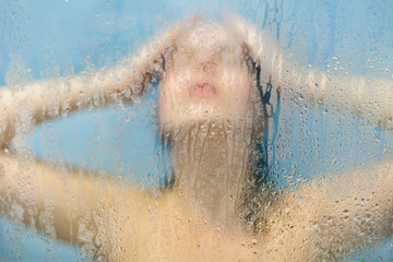 Relief and relaxation concept. Female model washes hair in douche, stands in shower cabine at bathroom, applies shampoo, closes eyes as feels relaxed and carefree, rests after hard work