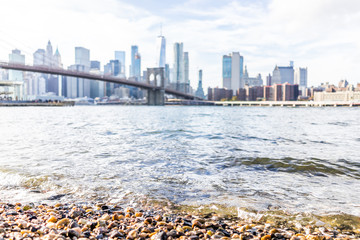 Rocky pebble beach shore water in east river with view of NYC New York City cityscape skyline and bridge, nobody in Brooklyn