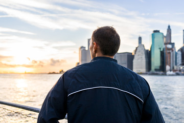 Back of young man outside outdoors in NYC New York City Brooklyn Bridge Park by east river,...