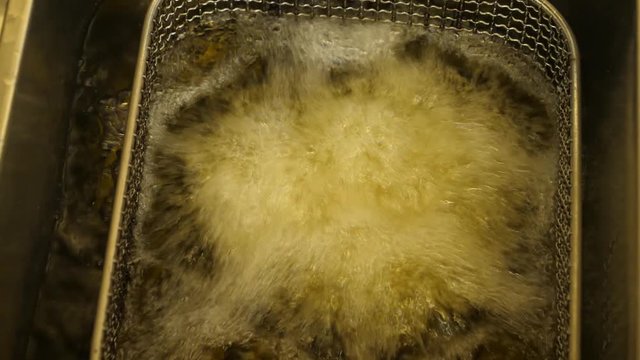 Falafel balls fall into boiling oil in the grate