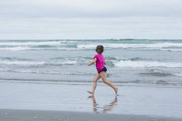 Very Brave Small 4 or 5 Years Girl in preschool age walking in the Ocean with bright blue water, Pacific Ocean, Oregon Coast, USA, Family Vacation