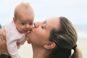 Close-up Portrait of Young Beautiful Mother Holding Her Newborn Baby Girl at Hot Summer Day, Sea Side, Pacific Ocean Beach, Family Vacation, Oregon USA, Happy Motherhood Concept, Happy Family Concept